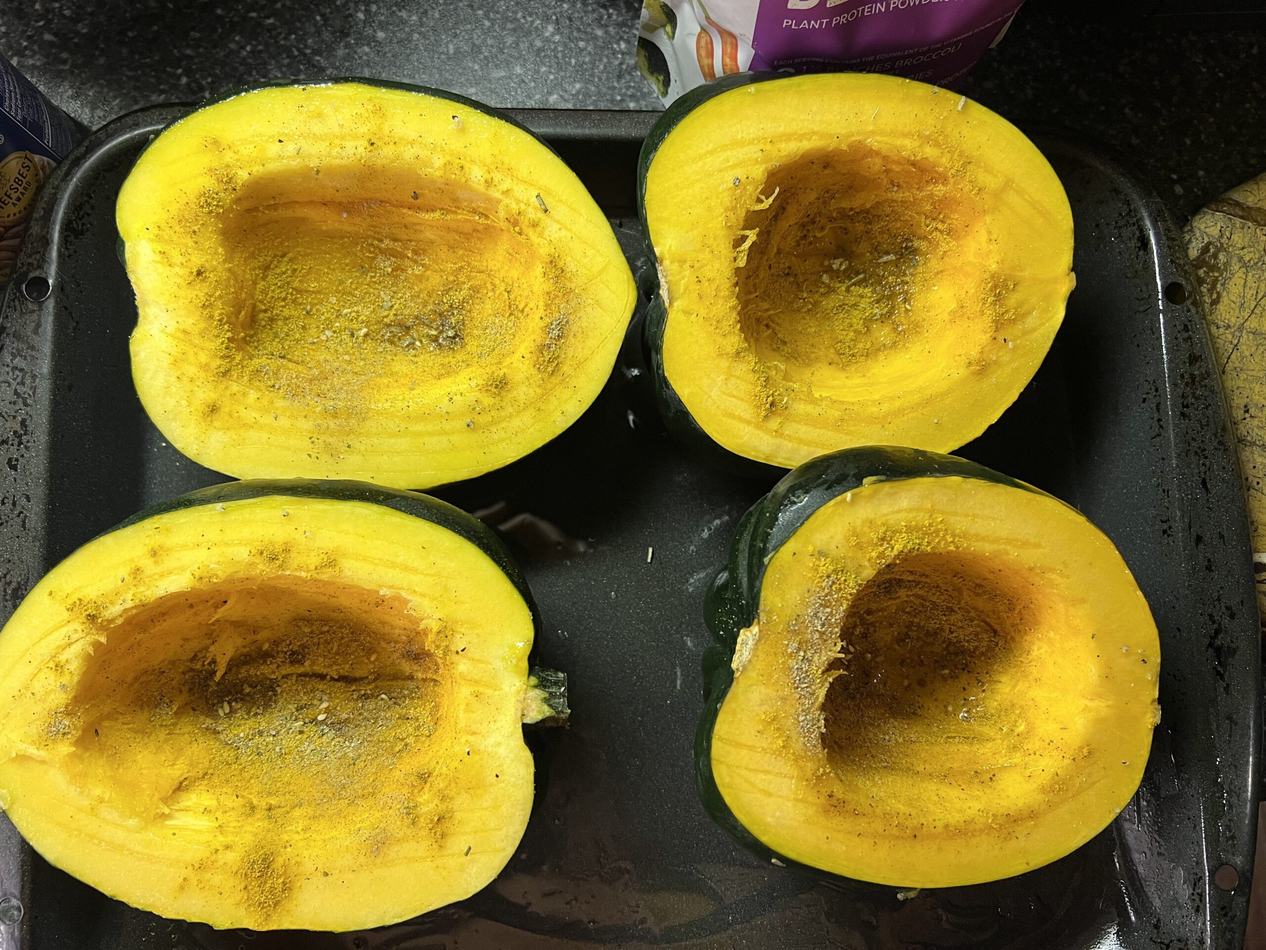Four halves of squash in a roasting pan, skin-side down, grooved with a fork and sprinkled with spices.